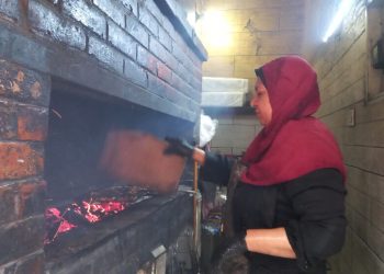 امرأة تقف وسط ألسنة الفحم المشتعلة لتأمين مصدر دخلها