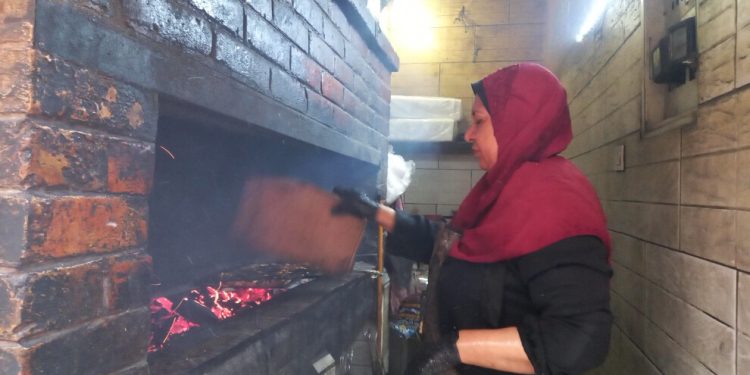 امرأة تقف وسط ألسنة الفحم المشتعلة لتأمين مصدر دخلها